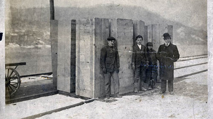 This photograph, taken on the banks of the Monongahela River, shows the arrival of rough box caskets in Fayette City, Fayette County, following the Naomi mine explosion. Robert R. Hawker, a 15-year-old wagoneer for the coal company, helped with the delivery and is second from right.