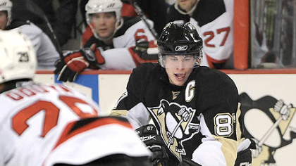 The Penguins' Sidney Crosby goes down on one knee and takes the puck away from the Devils' Johnny Oduya.