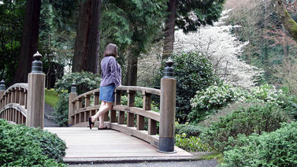A visitor pauses at the Moon Bridge, a landmark in the Japanese Garden of Portland.