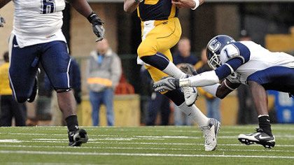 West Virginia's Pat White carries the ball away from Connecticut's Dan Davis (6) and Darius Butler (1) during the first half.