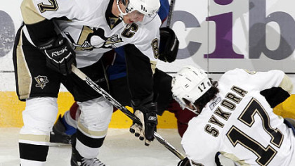Penguins center Sidney Crosby, center, checks Colorado Avalanche center Paul Stastny into the boards as Penguins right winger Petr Sykora, front, of the Czech Republic, comes in to pick up the loose puck in the third period of the Avalanche's 3-2 victory last night in Denver.