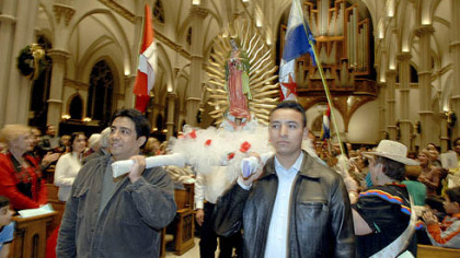Ruben Ruiz, left, and Jose Arellano carry the statue of Our Lady of Guadalupe into St. Paul Cathedral in Oakland last night.